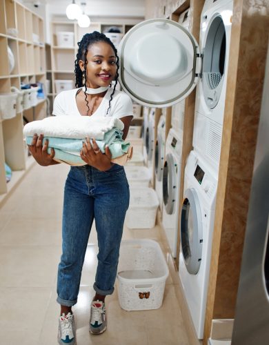 cheerful african american woman with towels in hands near washin